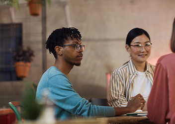 Three students talking outside in campus gardens
