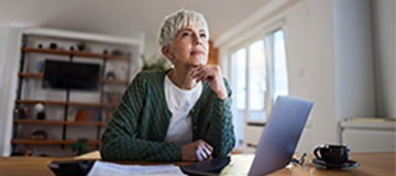 A woman looks thoughtfully at her laptop